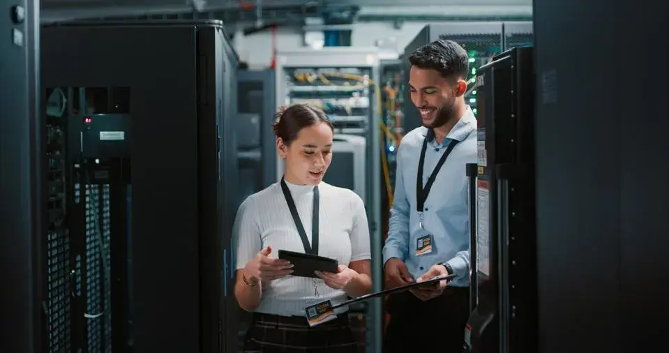 Female and male standing in the middle of a server room.