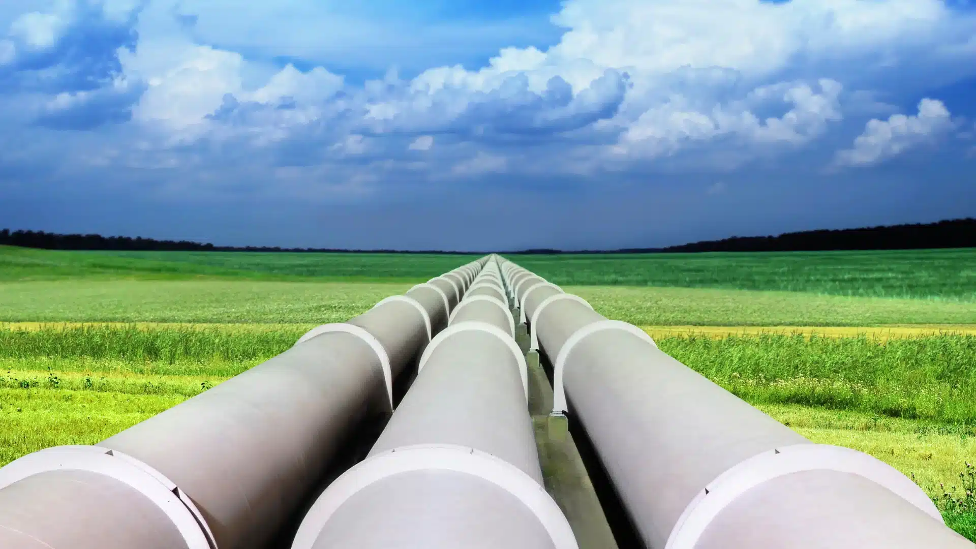 3 pipelines side by side over a green field with a blue sky