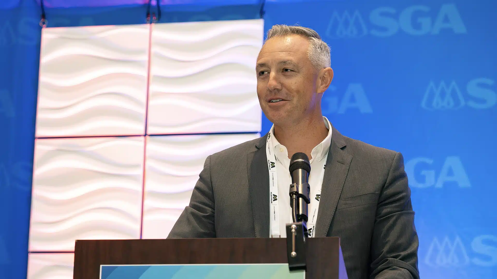 man in suit standing at a podium speaking